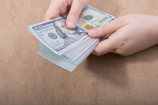 istock Hand holding American dollar  isolated on wooden background 1004355856