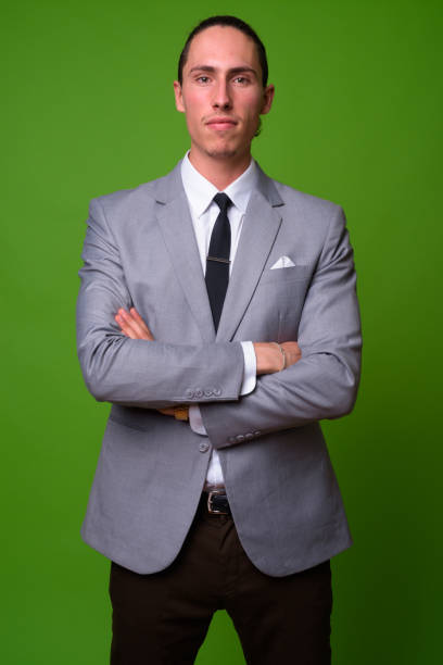 istock Young handsome businessman against green background 1004363726