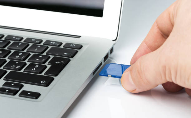 istock Cropped Hand Putting Memory Card In Laptop At Table 1004379176