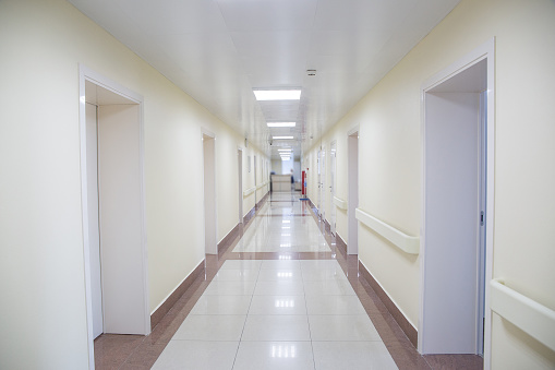 Empty hospital corridor. Yellow walls, many doors.