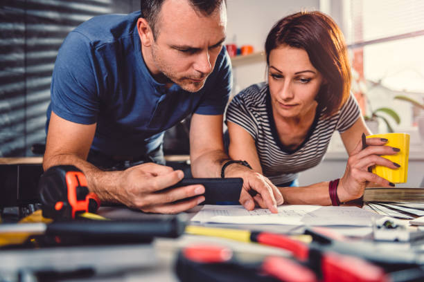 couple looking at blueprints during kitchen renovation - home decorating interior designer blueprint planning imagens e fotografias de stock