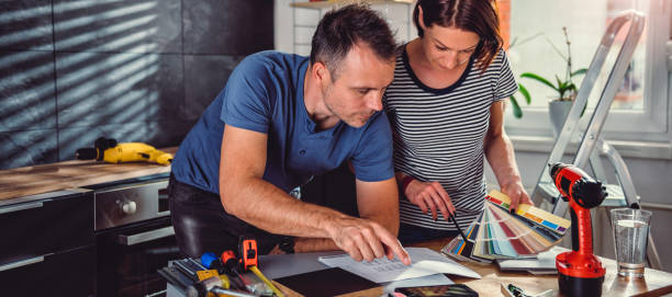 casal olhando plantas durante a renovação da cozinha - home decorating interior designer blueprint planning - fotografias e filmes do acervo