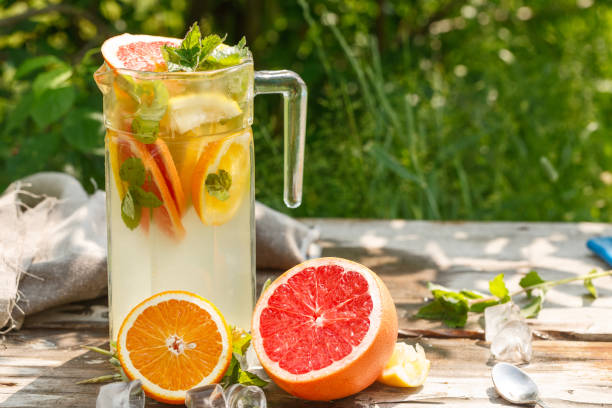 istock citrus lemonade in glass with mint. Orange. Grapefruit and lemon. On greenery background. 1004384372
