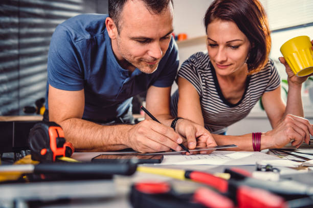 couple looking at blueprints during kitchen renovation - home decorating interior designer blueprint planning imagens e fotografias de stock