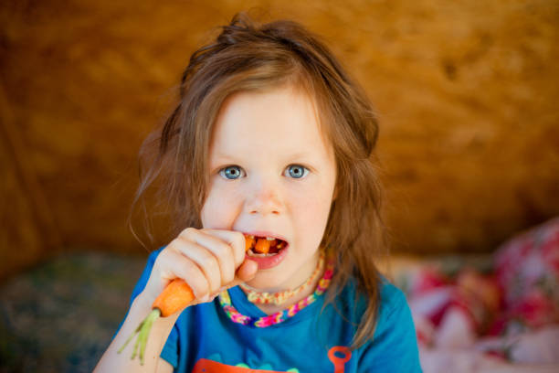 istock Little girl eats a carrot 1004391668