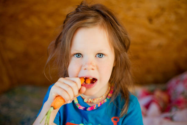 istock Little girl eats a carrot 1004391670