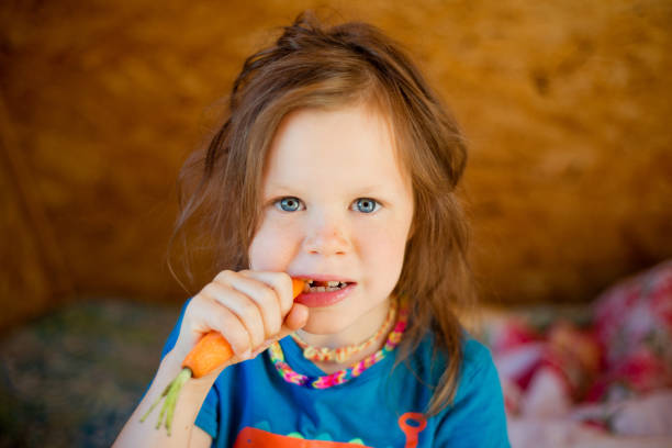 istock Little girl eats a carrot 1004391676