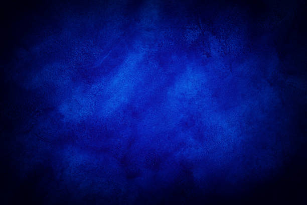 istock Dark blue marble or cracked concrete background with some light in the center 1004392016