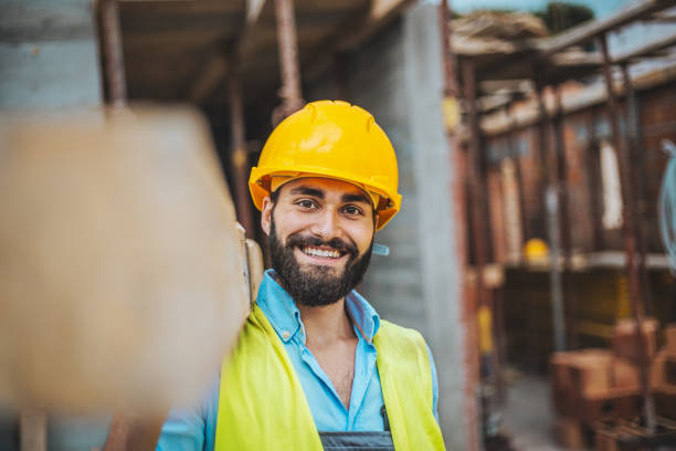 istock Portrait of construction worker with timber on shoulder 1004392670