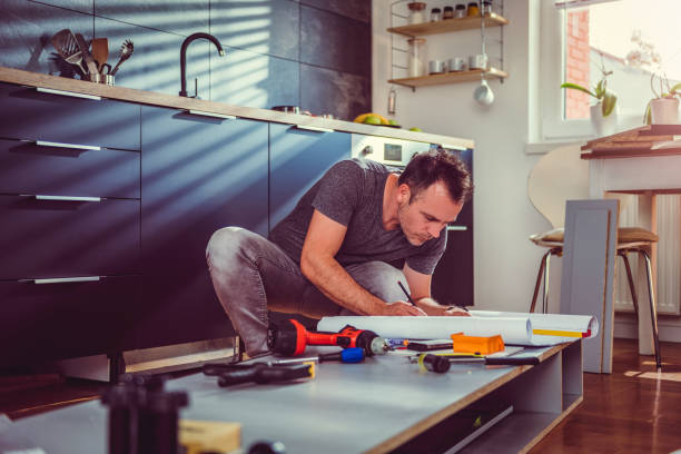 man checking blueprints while building kitchen cabinets - craft craftsperson photography indoors imagens e fotografias de stock