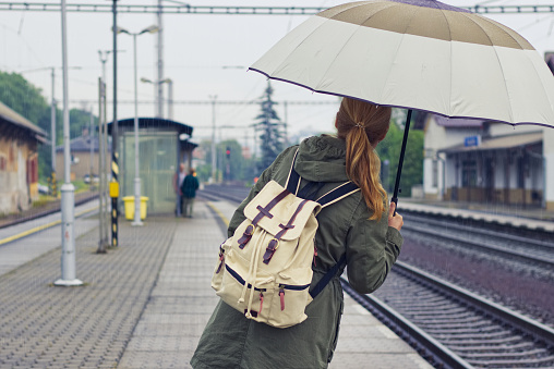 Female backpacker standing at platform of train station.