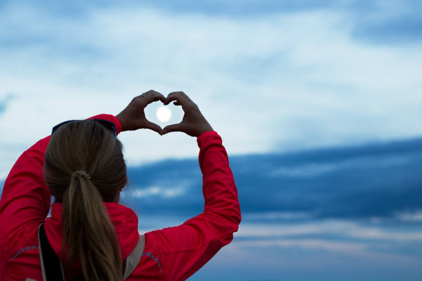 istock Woman making heart symbol by hands at full moon. 1004449178