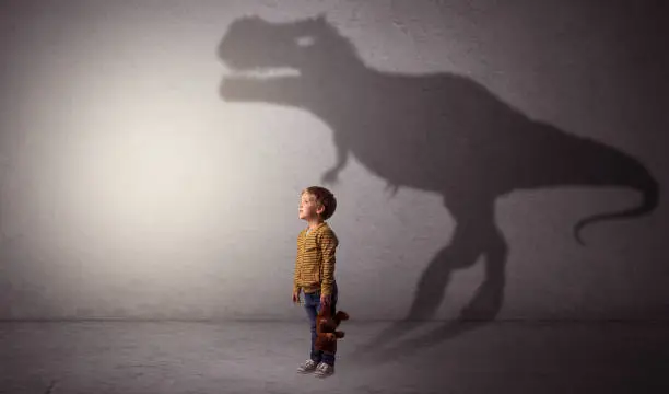 Photo of Dinosaurus shadow behind cute boy