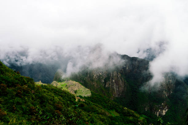 istock Distant view of Machu Picchu citadel among clouds with valley view 1004490204