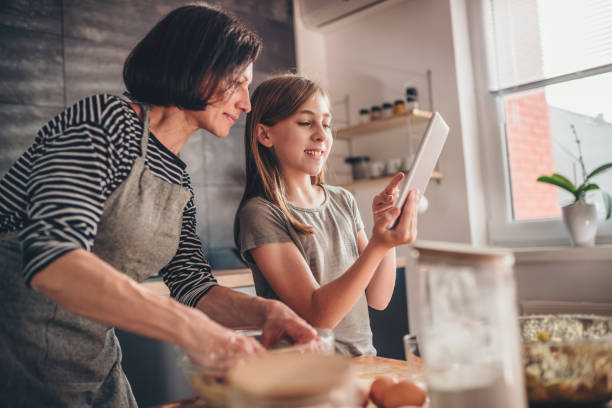 madre e figlia cercano ricetta torta di mele sul tablet - child digital tablet mother teaching foto e immagini stock