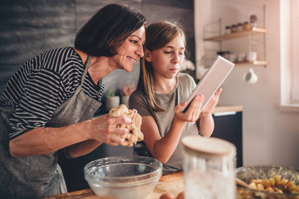 Mother and daughter searching apple pie recipe on the tablet stock photo