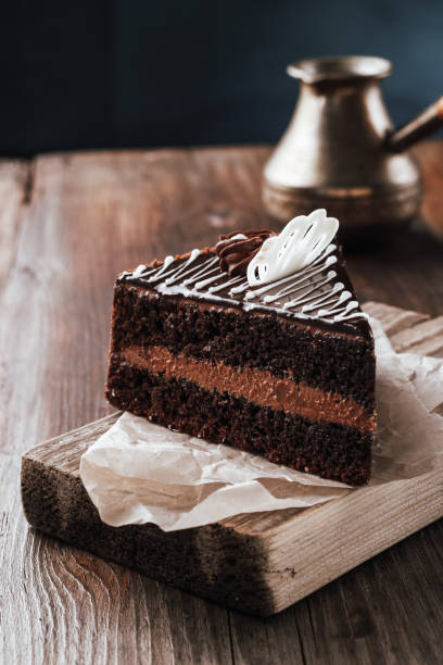 istock Chocolate cake side view on a cutting board rustic on a wooden table. 1004504220