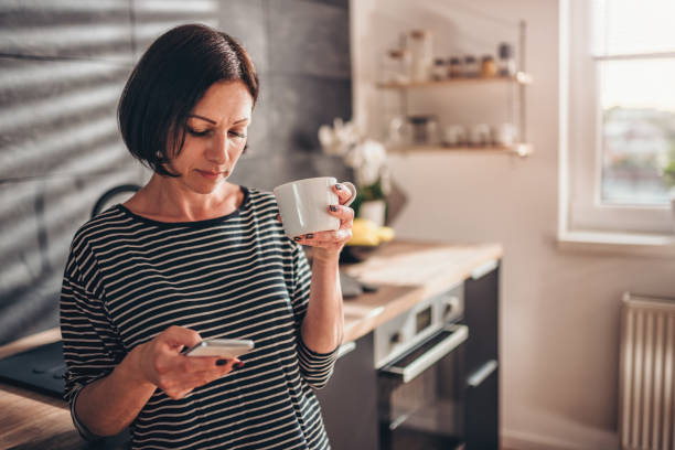 istock Woman standing in the kitchen and using smart phone 1004506646