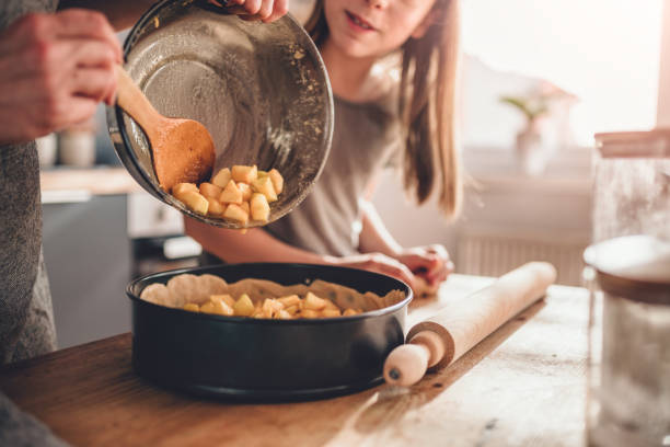 Woman pouring apple filling into baking pan