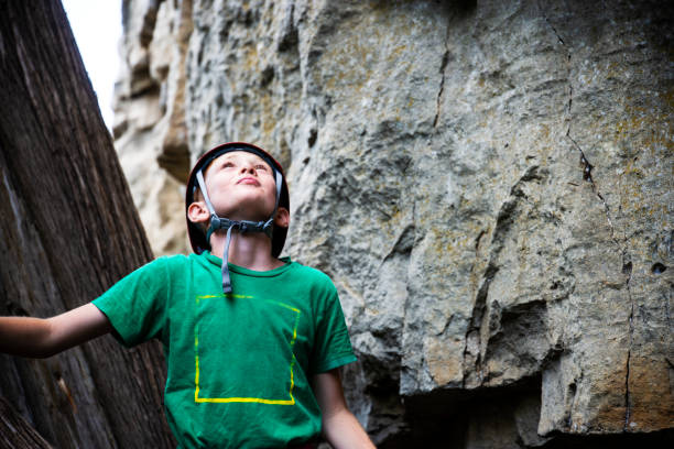 A young rock climber waiting to ascend a rock face during a rock climbing camp.