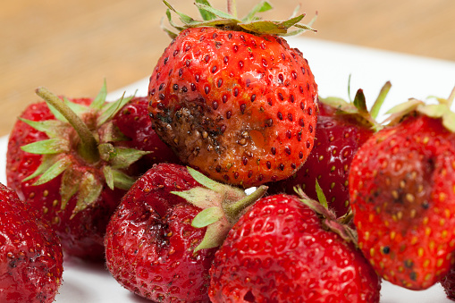Fresh strawberries in a bowl on wooden kitchen table