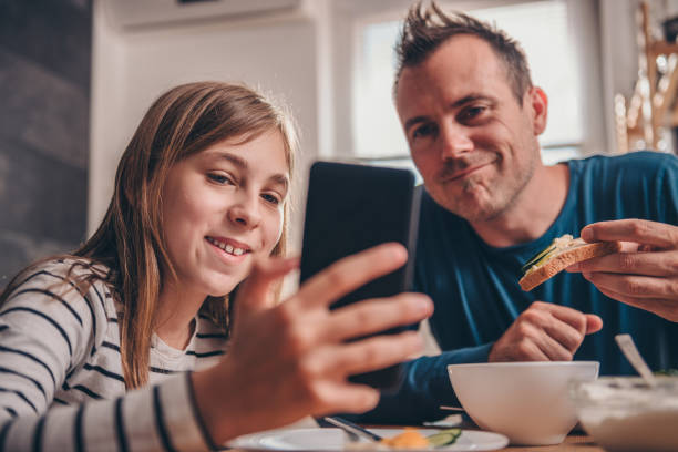 딸이 아버지를 스마트 휴대 전화에 비디오 표시 - family dining table breakfast eating 뉴스 사진 이미지
