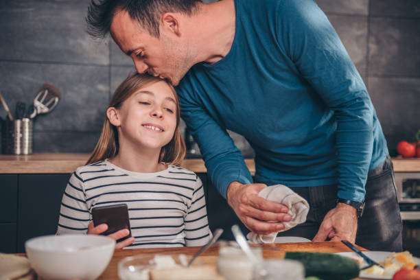 istock Father clearing table after breakfast and kissing daughter 1004540426