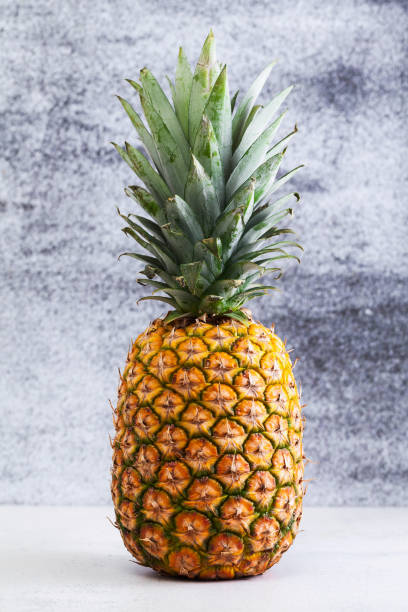 istock A whole ripe pineapple on a table on a gray background. 1004545950