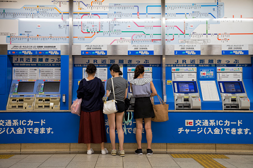 People buying train tickets at automatic ticket machines in Kyoto train station, Japan