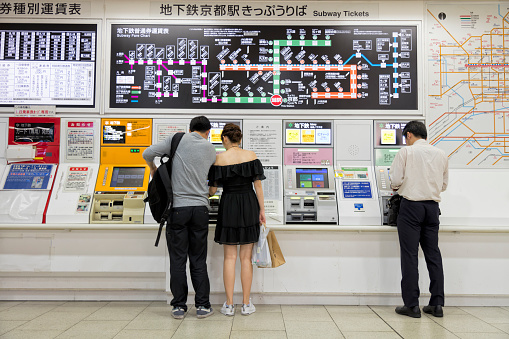 People buying train tickets at automatic ticket machines in Kyoto subway station, Japan