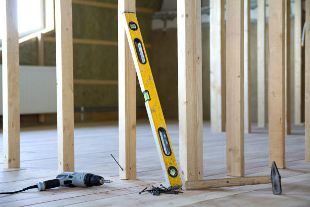 istock Close-up of professional tools: electrical screwdriver, level and measuring tape on background of wooden frame for future wall in attic room under reconstruction. Renovation and improvement concept. 1004561584