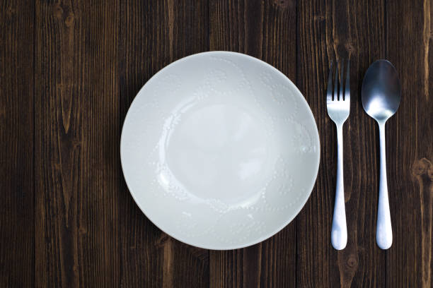 istock Empty plate or white dish with spoon and fork on wooden table background, Top view, eating concept. 1004564306