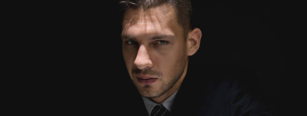 istock Face of tricky sly man staring at the camera in dark shadow 1004566576