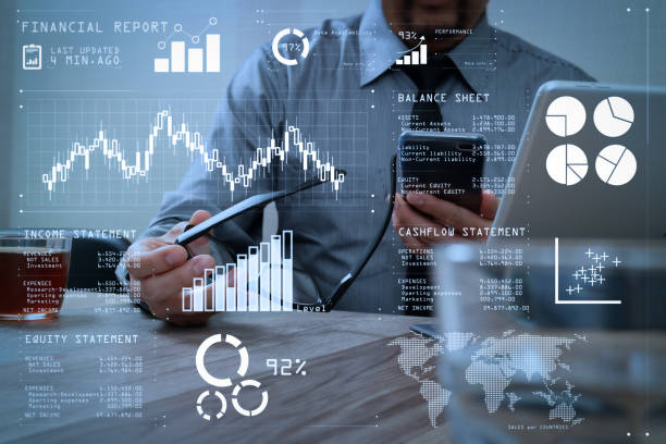 istock success businessman hand using eyeglass,smart phone,digital tablet docking smart keyboard on wood desk 1004573882