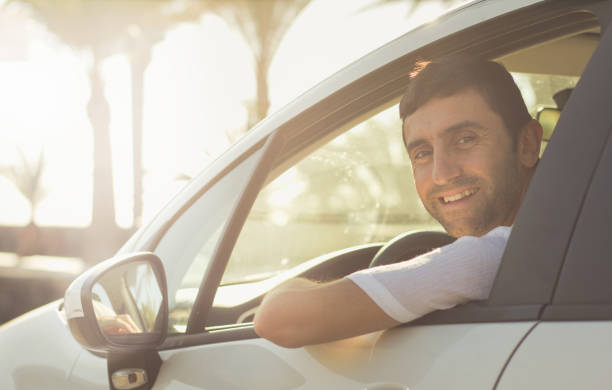 istock Smiling man looking back out of window of white compact vehicle 1004608254