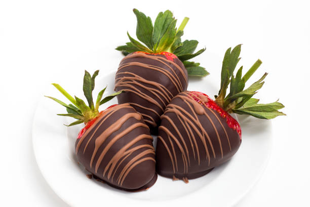 istock Close up of three chocolate covered strawberries on a white plate 1004610926