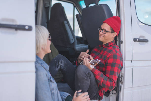 istock Hipster couple playing ukulele in their van on a camping trip 1004613510