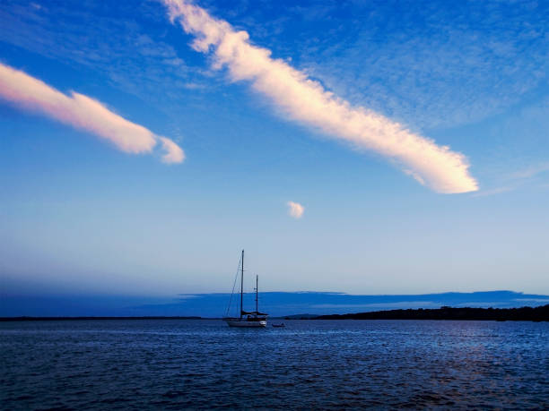 A brightly coloured Contrail and Cirrus sky cloudscape featuring a vapor trail cloud formation in a mid blue sky. New South Wales, Australia.