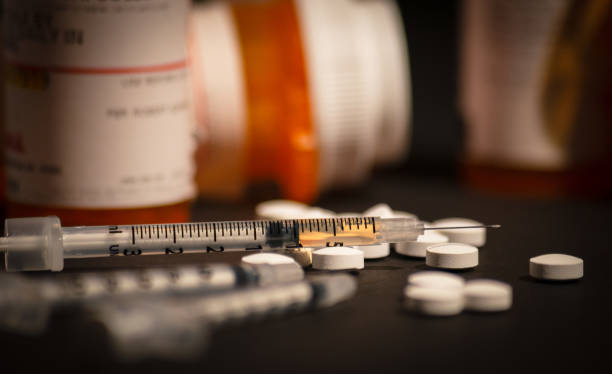 Loaded Syringe and Opioids An injectable drug is loaded into a syringe while prescription medication is strewn about haphazardly. fentanyl stock pictures, royalty-free photos & images