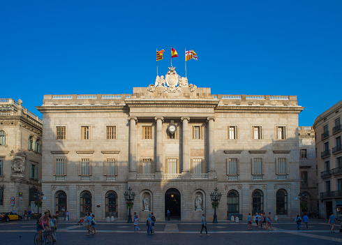 Barcelona, July 1, 2015: tourists stroll past the neoclassical main facade of Barcelona City Hall.