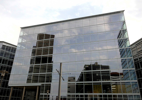 A modern building, in the media harbor Düsseldorf, with the reflection of other buildings in it. In black and white ,and in color.