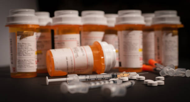 Loaded Syringe and Opioids An injectable drug is loaded into a syringe while prescription medication is strewn about haphazardly. fentanyl stock pictures, royalty-free photos & images