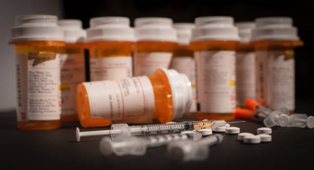 Loaded Syringe and Opioids An injectable drug is loaded into a syringe while prescription medication is strewn about haphazardly. methadone stock pictures, royalty-free photos & images