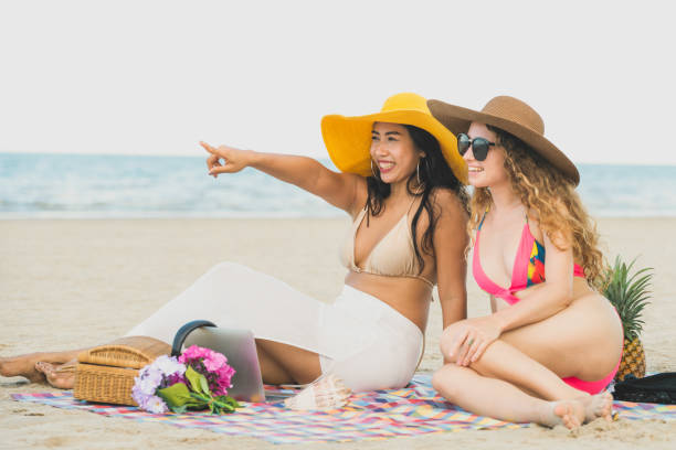 istock Happy women sitting on sand beach in summer. 1004679002