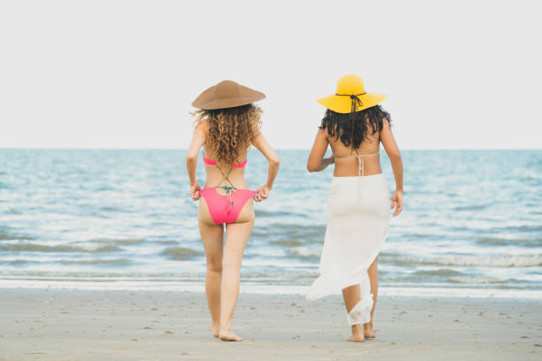 istock Happy women go sunbathing at sand beach in summer. 1004679526