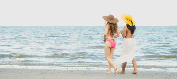 Happy women go sunbathing at sand beach in summer.