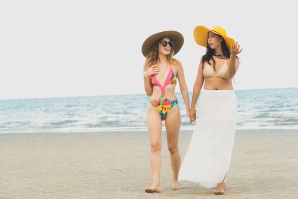 istock Happy women go sunbathing at sand beach in summer. 1004681026