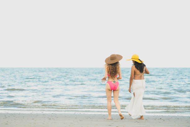 istock Happy women go sunbathing at sand beach in summer. 1004681028