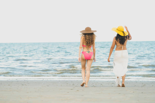 istock Happy women go sunbathing at sand beach in summer. 1004681034
