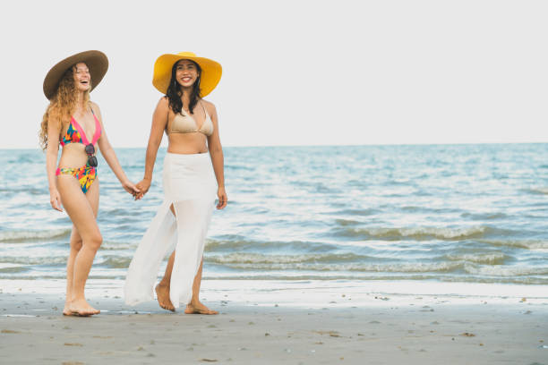 Happy women go sunbathing at sand beach in summer.